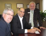 Tim Brown, left and Len Lifchus, both of the United Way, lean just a little on Fund Raising Campaign Chair Karmel Sakran, center, to write a cheque for the amount to got the total to $2,200,00 - a record for Burlington.