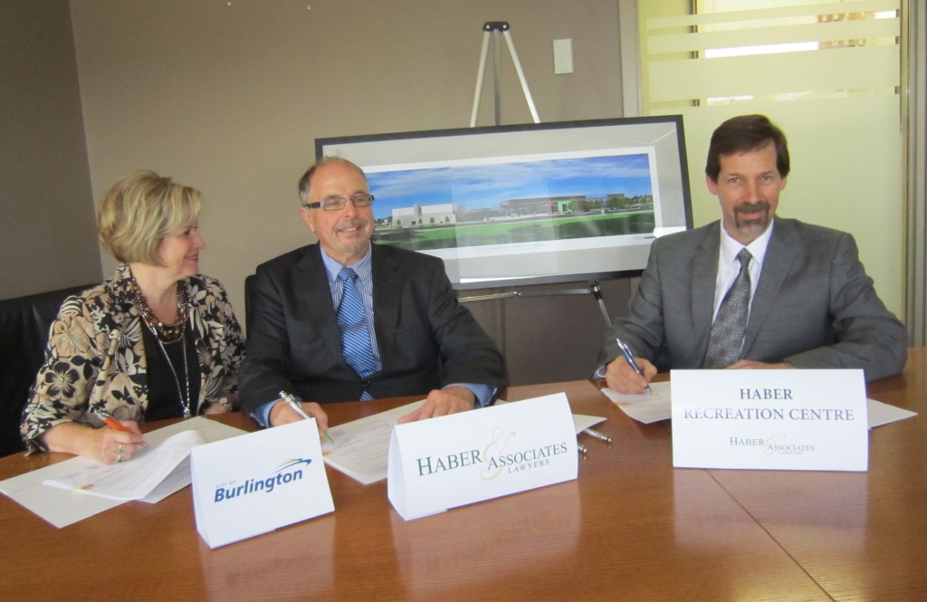 From the left, WArd 6 Councillor Blair Lancaster sitting in for MAyor Goldring who had to remain at Regional Concil to assure quorum, as she signs the 20 year $1.3 milion naming rights deal with Chris HAber in the Centre. Chris Glenn on the right is pleased with that much casj