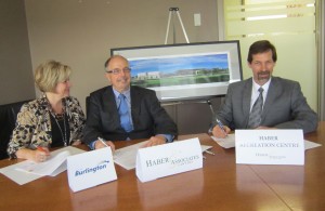 From the left, WArd 6 Councillor Blair Lancaster sitting in for MAyor Goldring who had to remain at Regional Concil to assure quorum, as she signs the 20 year $1.3 milion naming rights deal with Chris HAber in the Centre. Chris Glenn on the right is pleased with that much casj