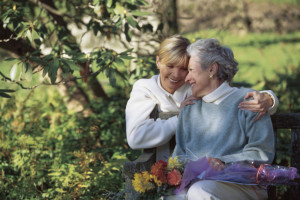 Adult daughter hugging mother with flower bouquet