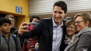 Liberal leader and prime minister-designate Justin Trudeau takes a selfie while greeting people at a subway station in Montreal, Quebec, October 20, 2015. Trudeau, having trounced his Conservative rivals, will face immediate pressure to deliver on a swathe of election promises, from tackling climate change to legalizing marijuana. REUTERS/Chris Wattie - RTS5CCS